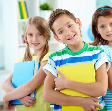 Children holding their workbooks and smiling