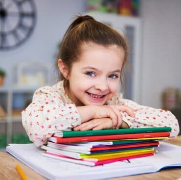 A girl resting on a stack of notebooks