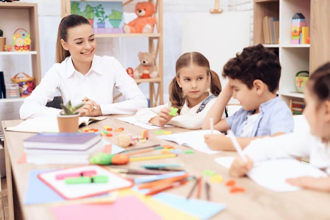 A teacher working at the table with children at Sunlight Childcare